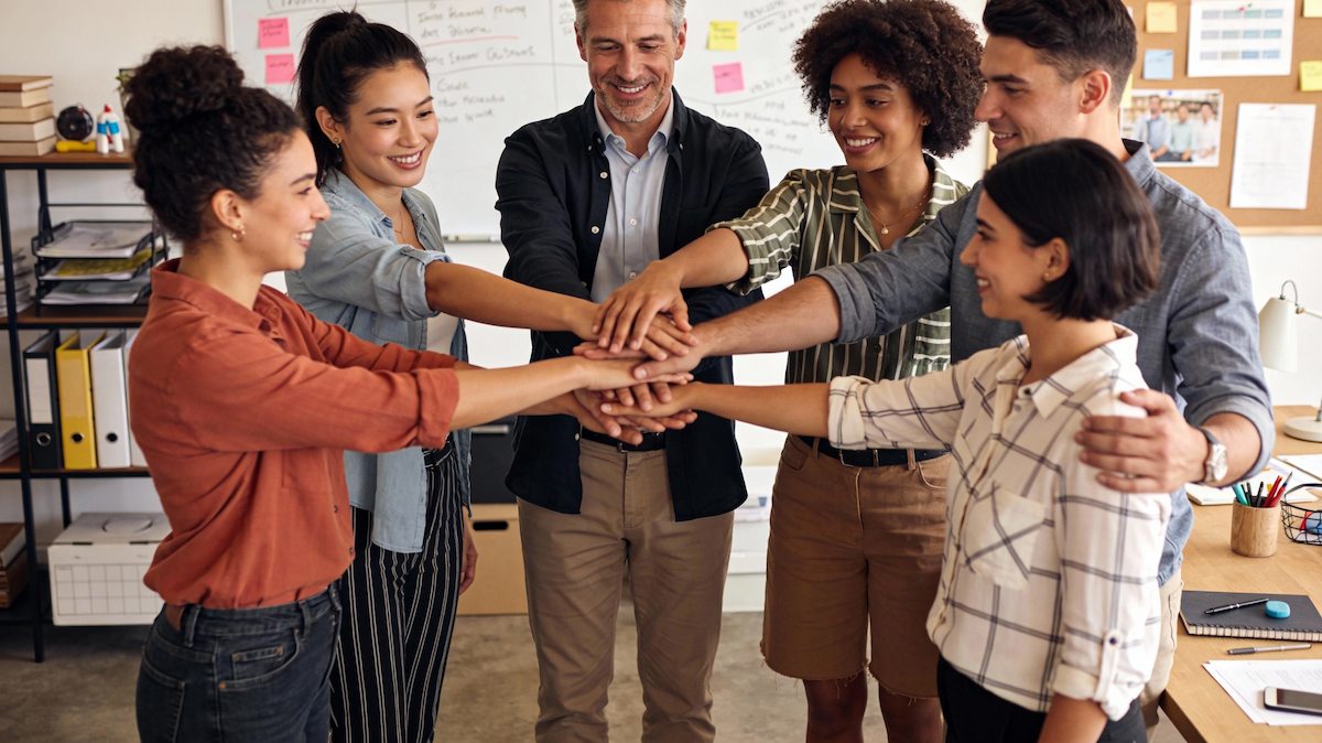 Thumbnail: Diverse business team putting hands together in unity demonstrating trust and collaboration for high-performing team culture