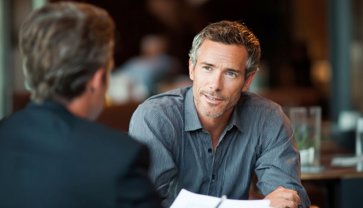 Small business owner discussing business health check results with advisor over documents at a table