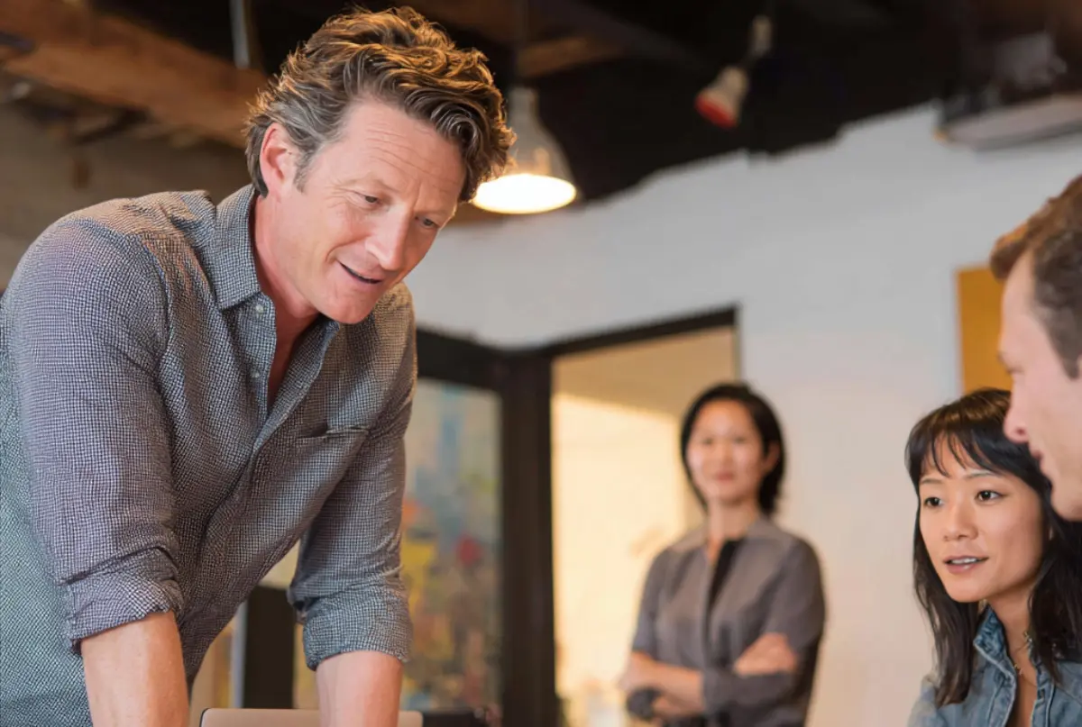 Small business leader mentoring team members in collaborative workspace identifying future leadership potential